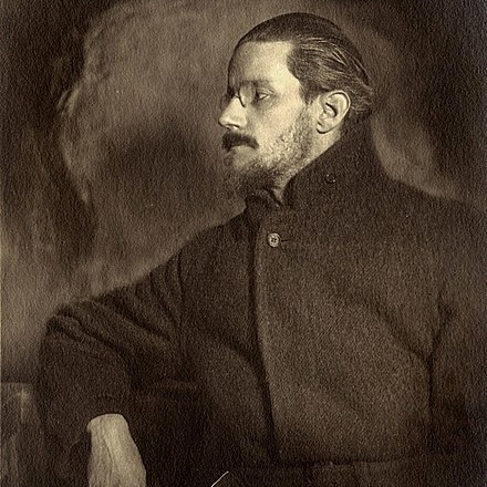 A profile of a somewhat pensive and moody looking Joyce in a dark overcoat.