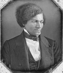 Black and white photo Frederick Douglas wearing a suit, face serious.
