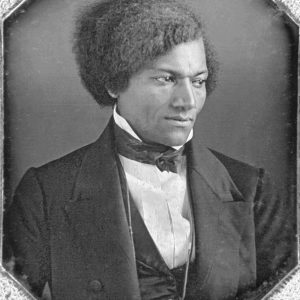 Black and white photo Frederick Douglas wearing a suit, face serious.