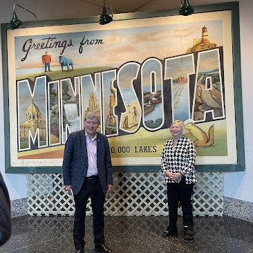 Ambassador Mulhall and wife, Greta arrive in Minnesota and pose under the MINNESOTA sign at the airport. 